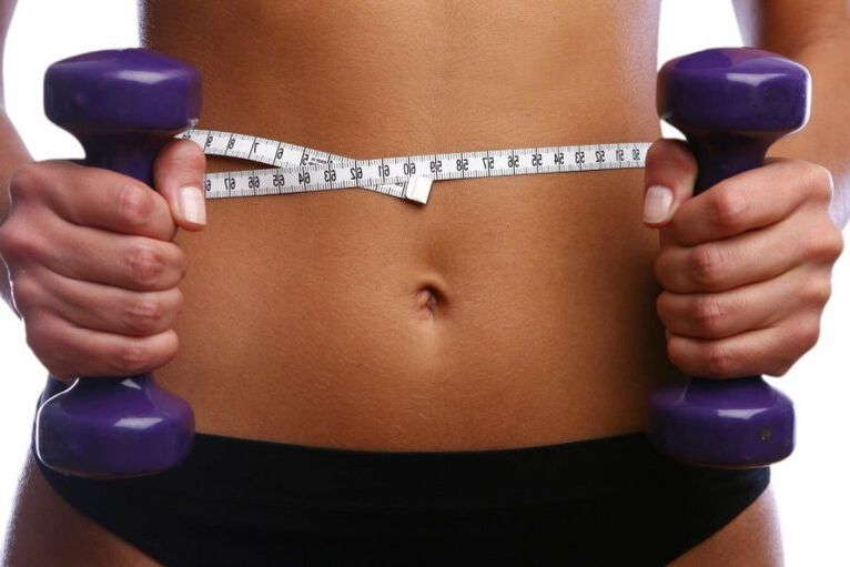 Halteres de fitness nas mãos de uma garota em forma